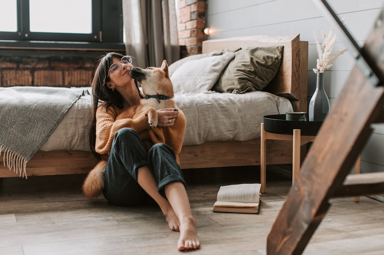 A heartfelt moment of a woman and Shiba Inu dog embracing in a cozy bedroom setting.